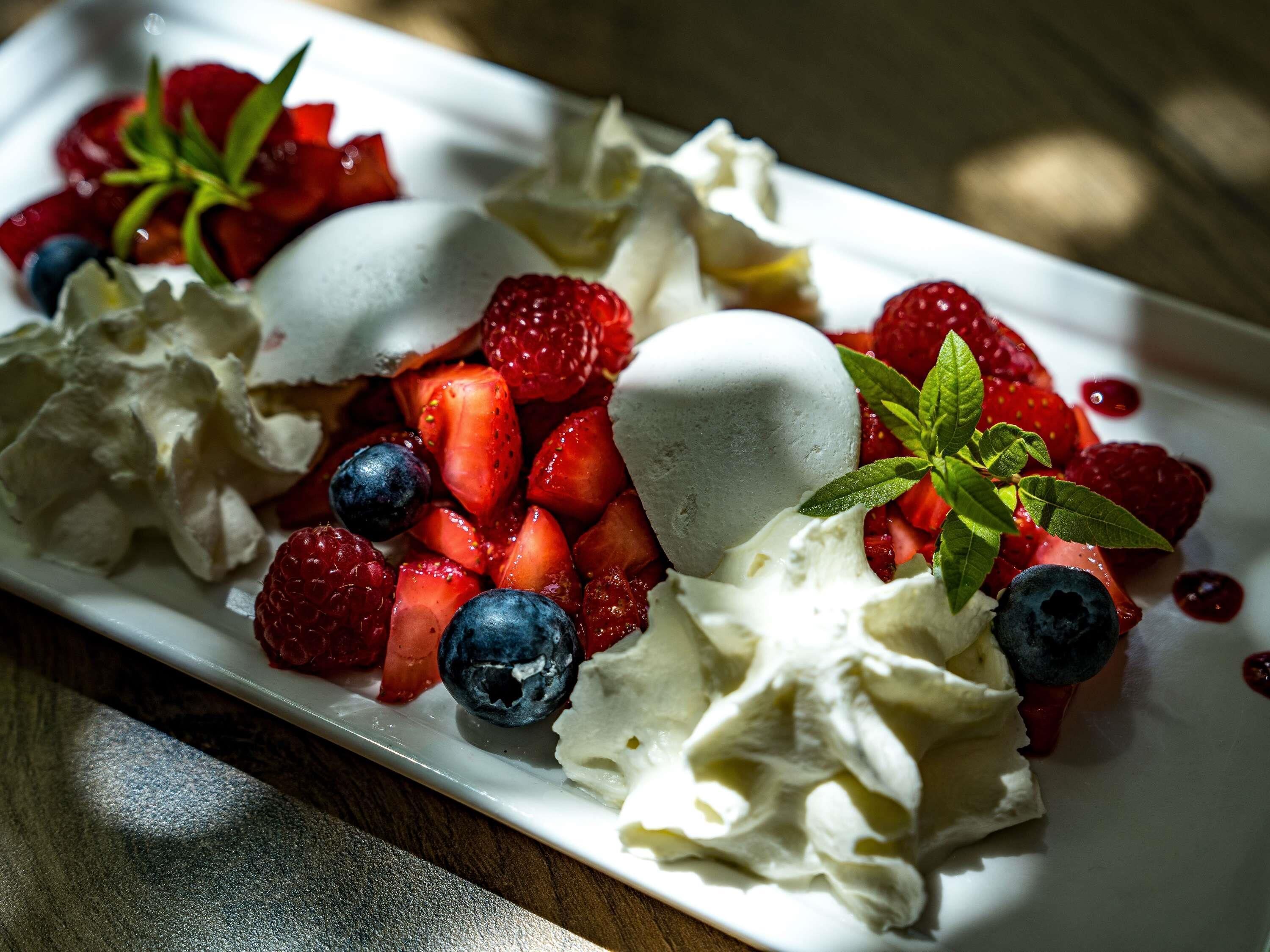 A dessert plate with meringue, strawberries, and blueberries.
