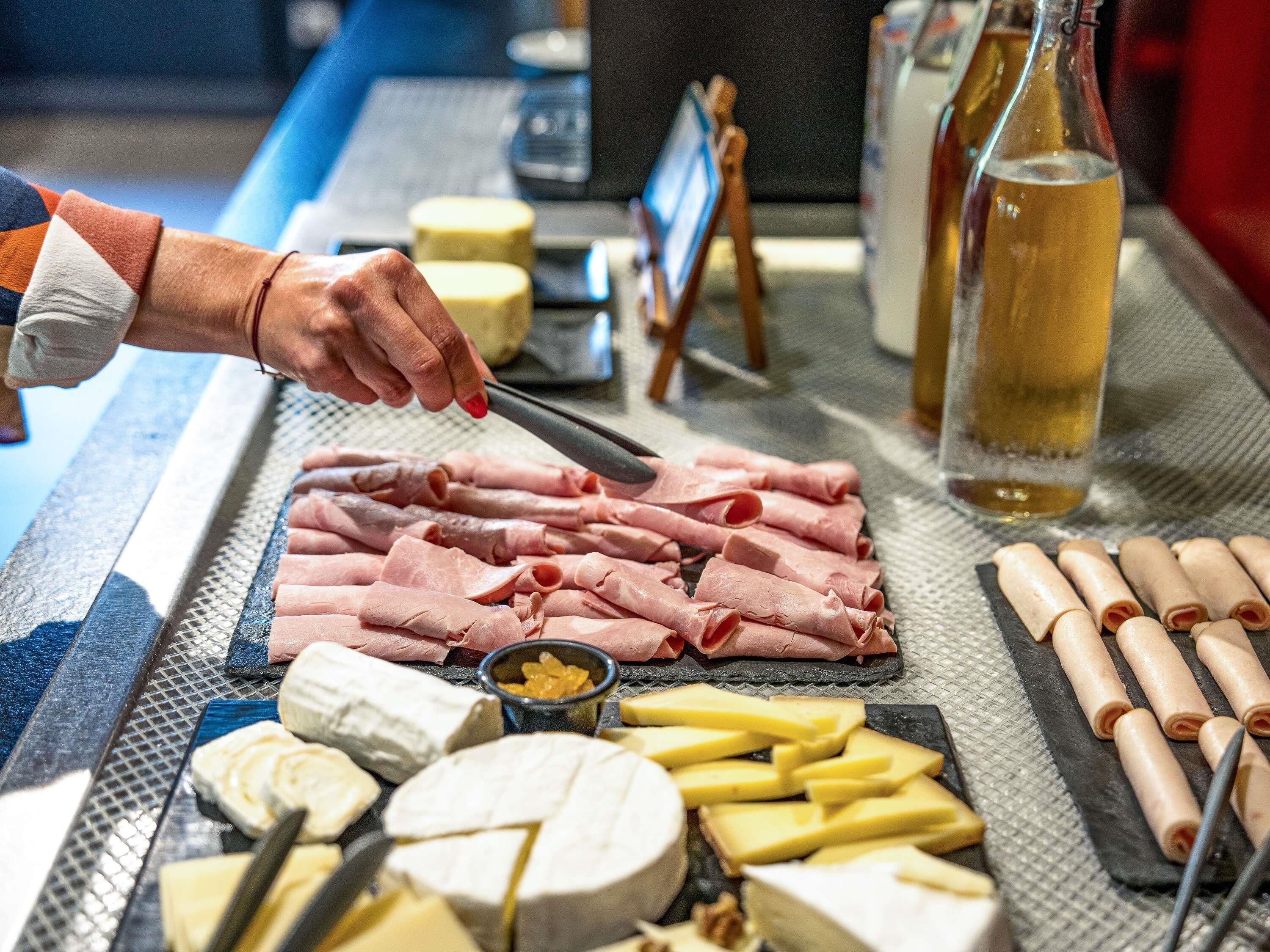 Tábua de frios com diversos queijos, carnes e uma garrafa de vinho.