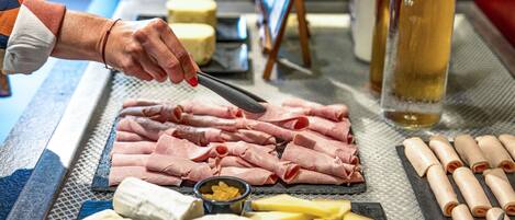 Tábua de frios com diversos queijos, carnes e uma garrafa de vinho.