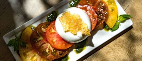 A rectangular plate with a poached egg, tomato slices, and a green sauce.