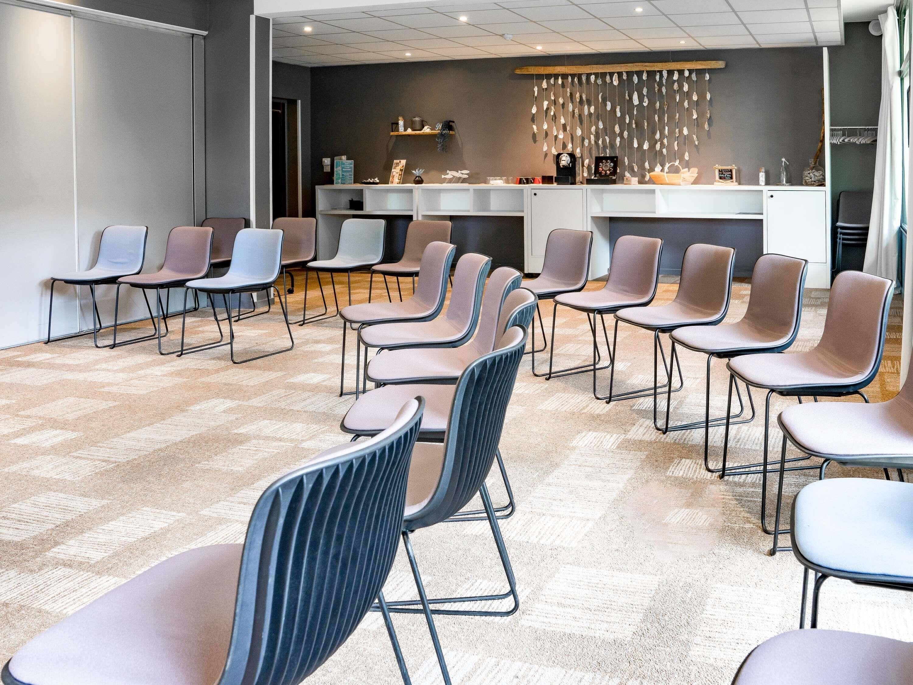 A conference room with rows of chairs, a reception desk, and a decorative wall hanging.