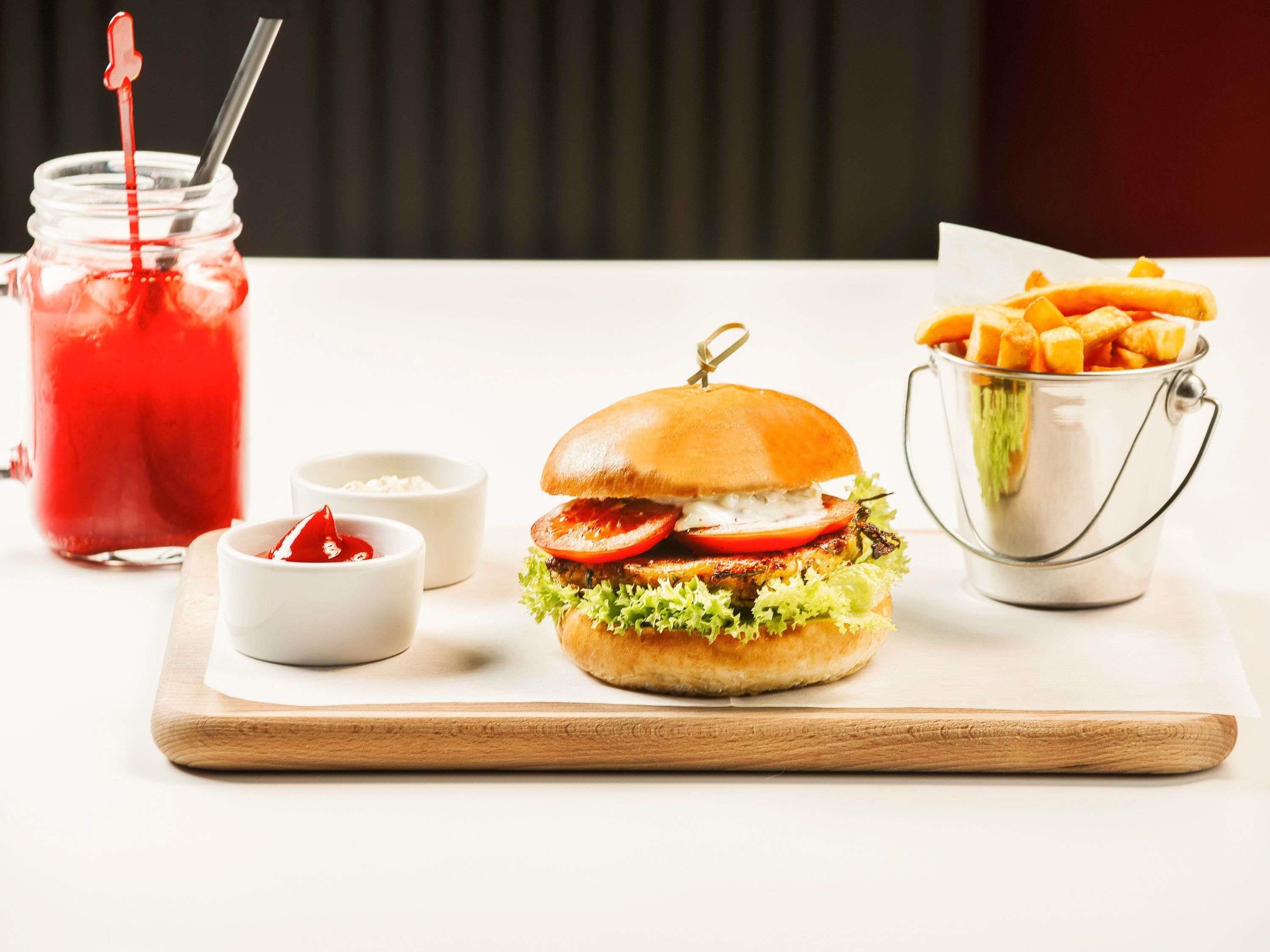 A meal setup with a burger, fries, ketchup, and a drink on a table.