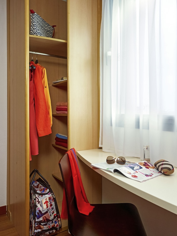 A study area with a desk, chair, and shelving unit containing books and a handbag.