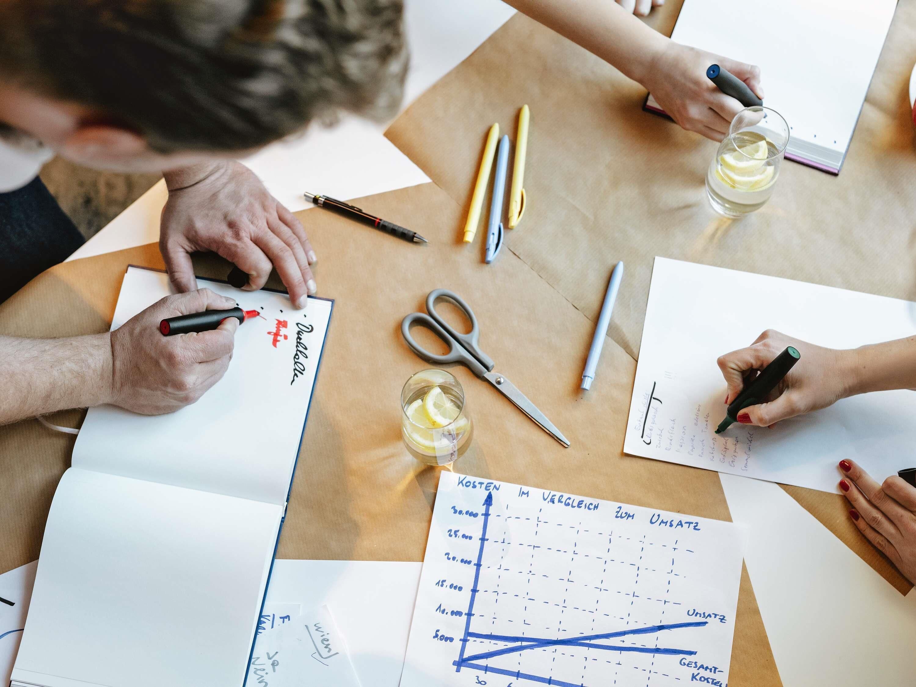 A group of people at a table with documents, pens, and a glass of water.