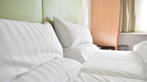 Une chambre d’hôtel avec un lit, une table de chevet et une fenêtre avec des rideaux.