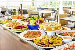 Een buffet met diverse gerechten, waaronder salades, taart en geroosterde aardappelen.