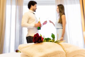Een hotelkamer met een bed, een rozenboeket en een fles champagne.
