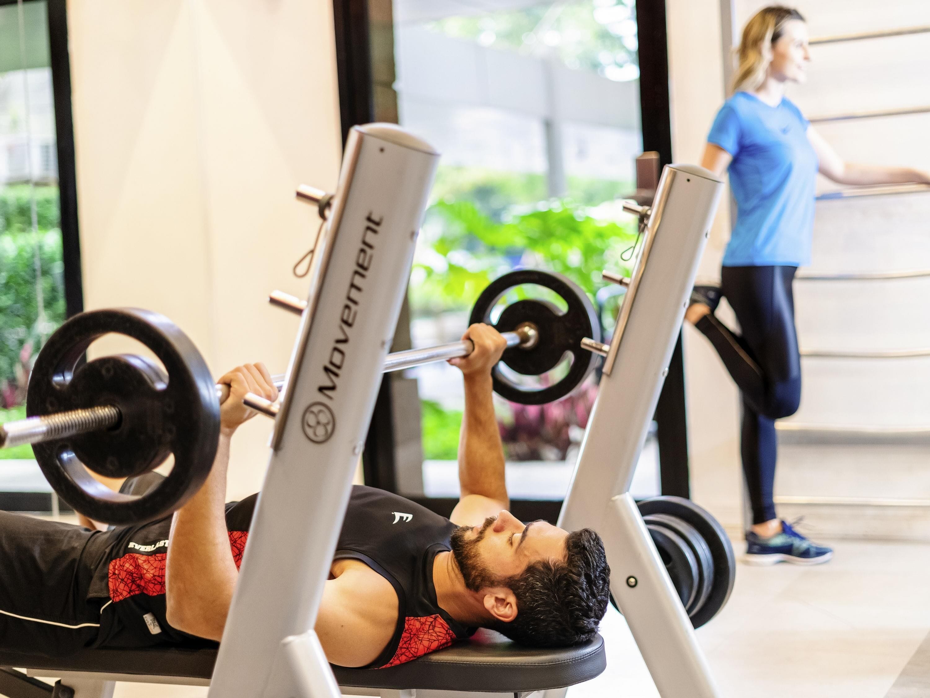 Une personne allongée sur un banc, utilisant un appareil de musculation avec une barre.