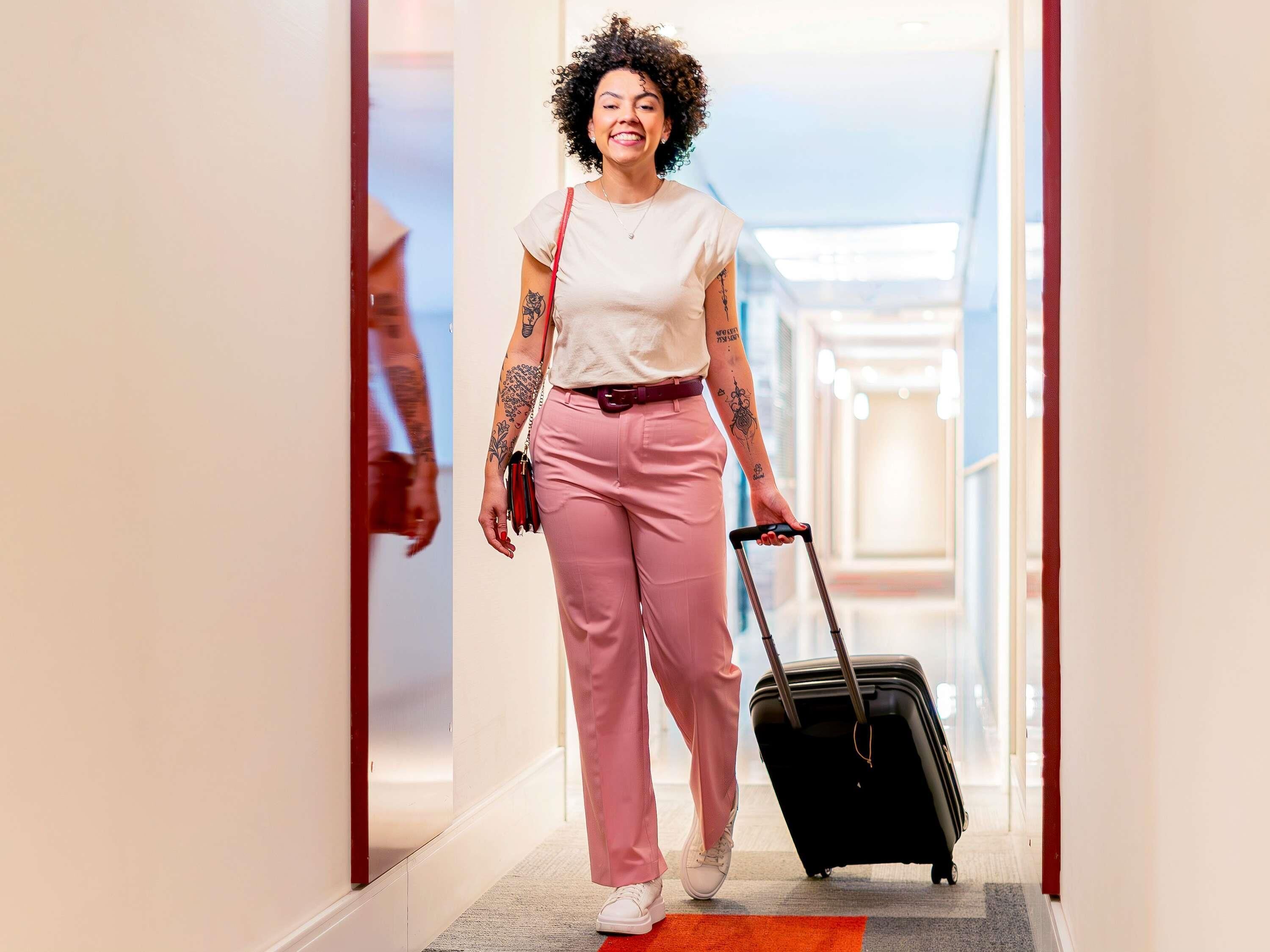 A person walking through a hallway with a suitcase.