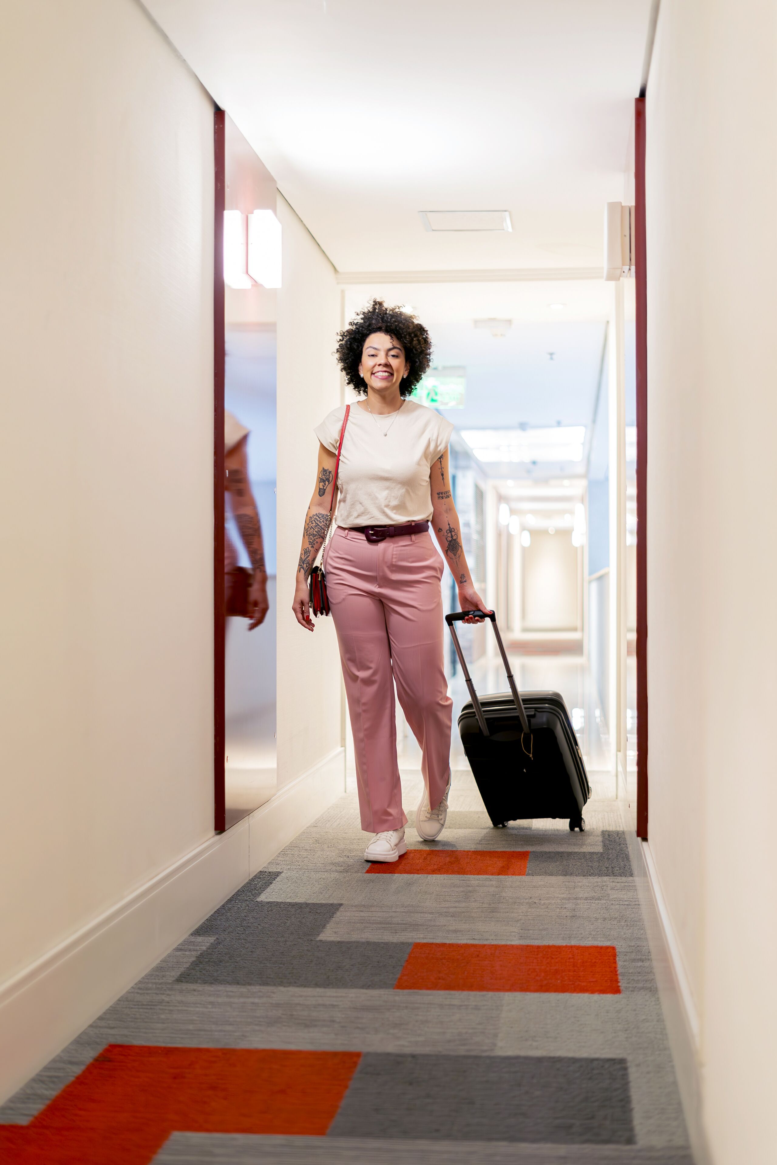 A person walking down a hallway with a suitcase.