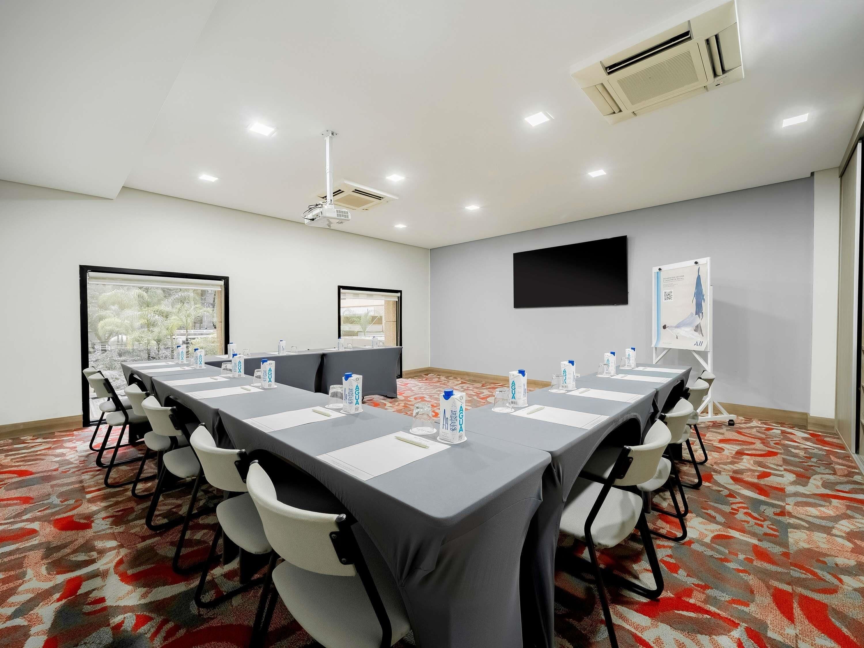 A conference room with a long table, chairs, a projector, and a whiteboard.