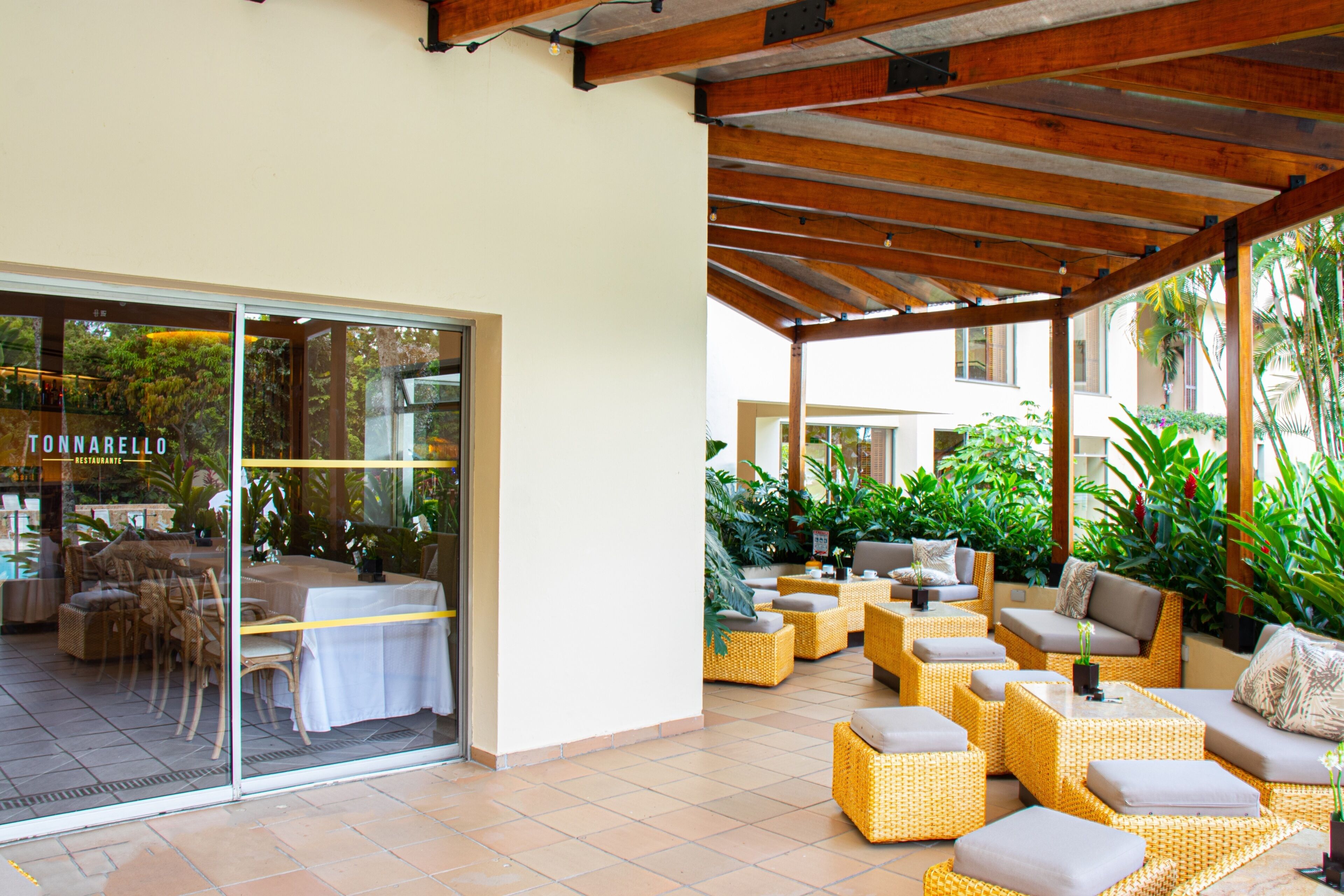 An outdoor patio area with wicker furniture, a glass door entrance, and a view of the surrounding greenery.
