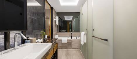 A modern bathroom with a large sink, mirror, and a walk-in shower.