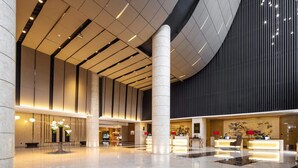 A spacious lobby with a high ceiling, a reception desk, and a large pillar. - ENLUX HOTEL  (Jinan)