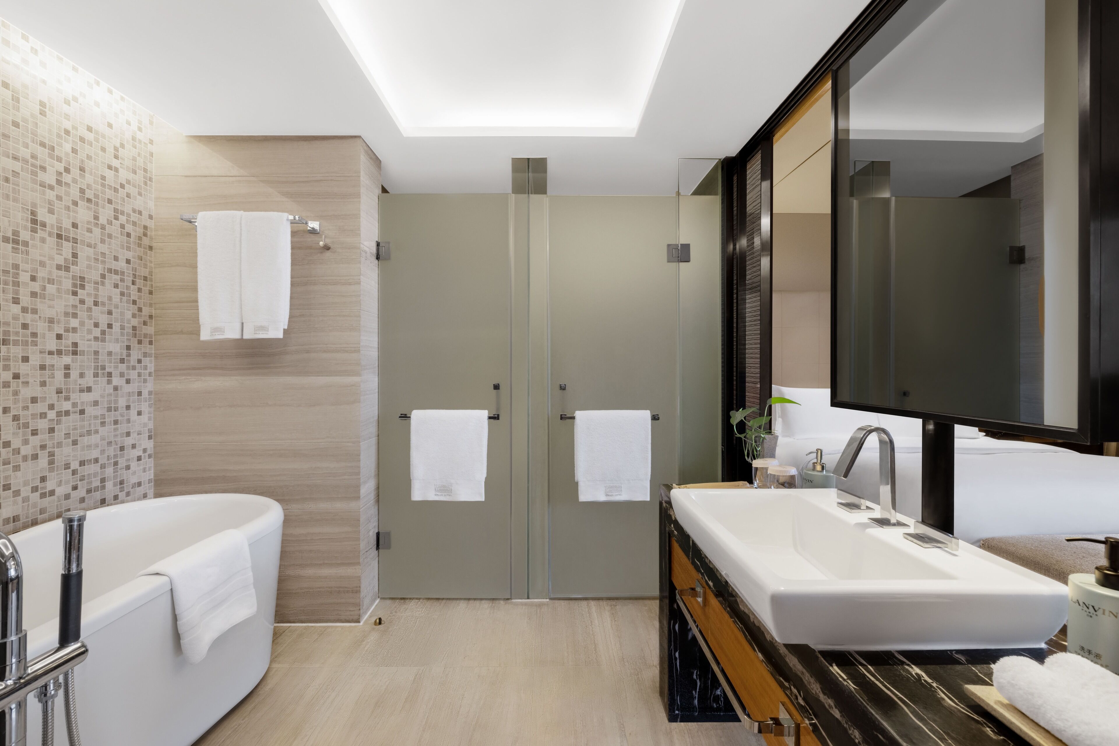 Une salle de bain moderne avec une baignoire sur pieds, un grand meuble-lavabo avec un miroir et deux portes.