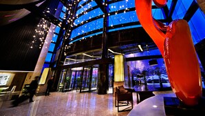 A modern lobby with a large glass facade, a prominent red sculpture, and a seating area. - ENLUX HOTEL  (Jinan)