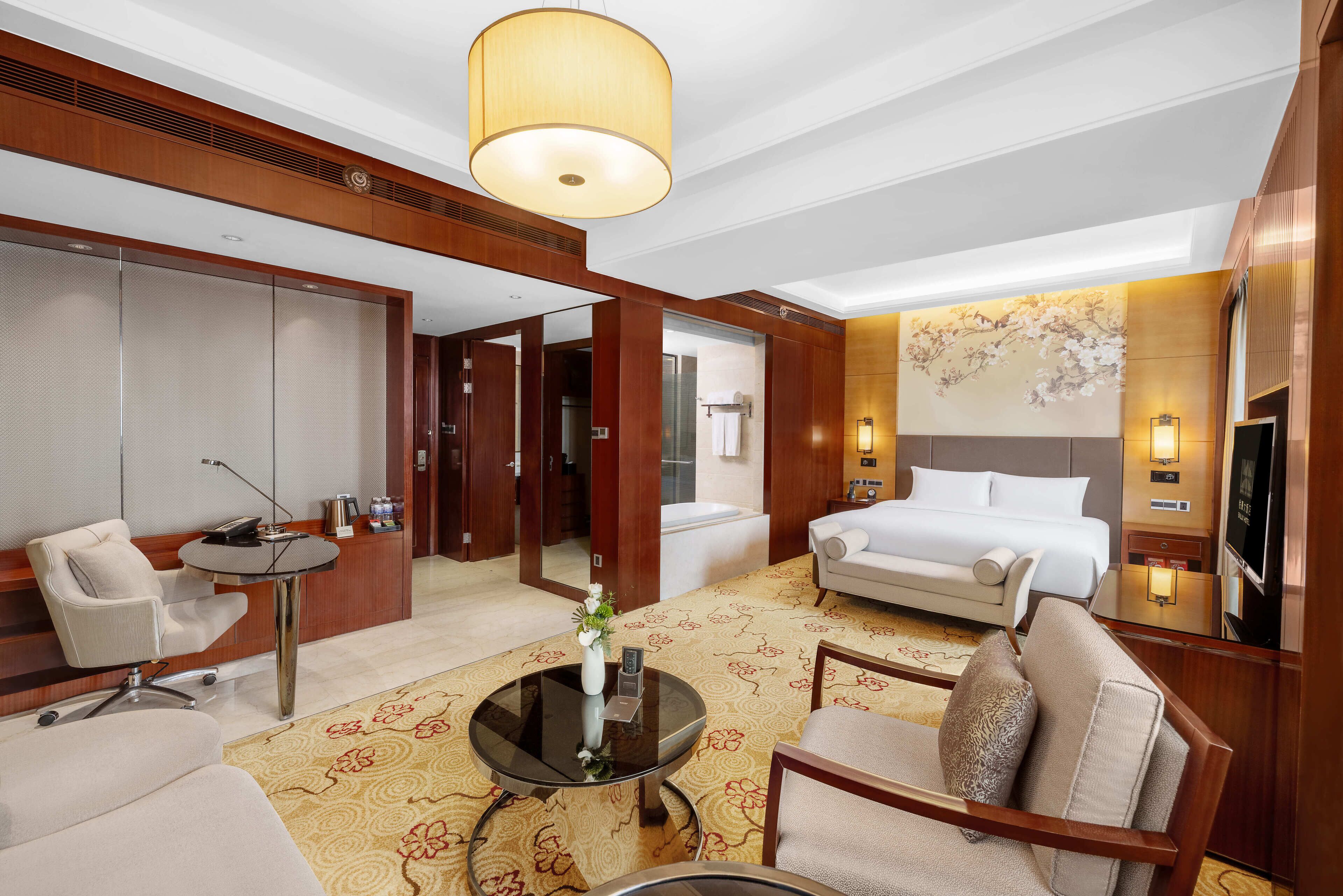 Habitación de hotel con cama, sofá, escritorio, silla, mesa de centro y televisor.