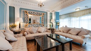A spacious living room with a large mirror, two sofas, a coffee table, and a chandelier. - The Empire Hotel & Spa (Llandudno)