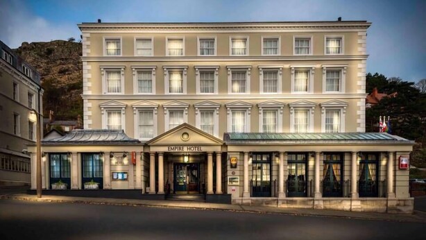 A large, multi-story hotel with a classic facade, featuring a central entrance with columns and a sign that reads "EMPIRE HOTEL". - The Empire Hotel & Spa (Llandudno)