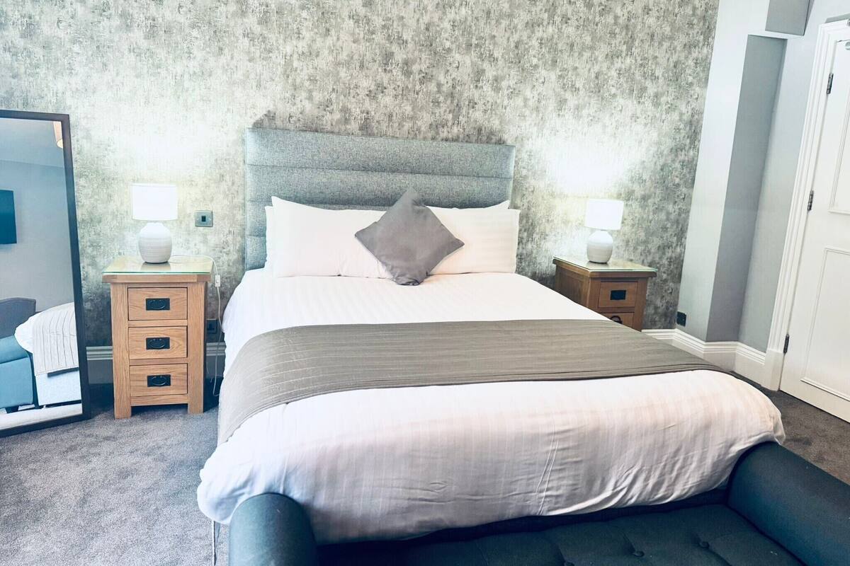 A neatly arranged bedroom with a large bed, two bedside tables, and a wardrobe.