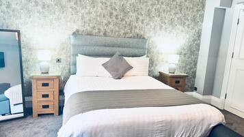 A neatly arranged bedroom with a large bed, two bedside tables, and a wardrobe.