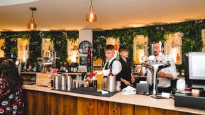A bar area with wooden counter, bar stools, and a variety of bottles and glasses. - The Oaklands Hotel (Norwich)