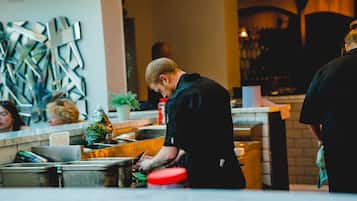 A person working at a counter in a modern kitchen area with metal appliances and a decorative wall piece.