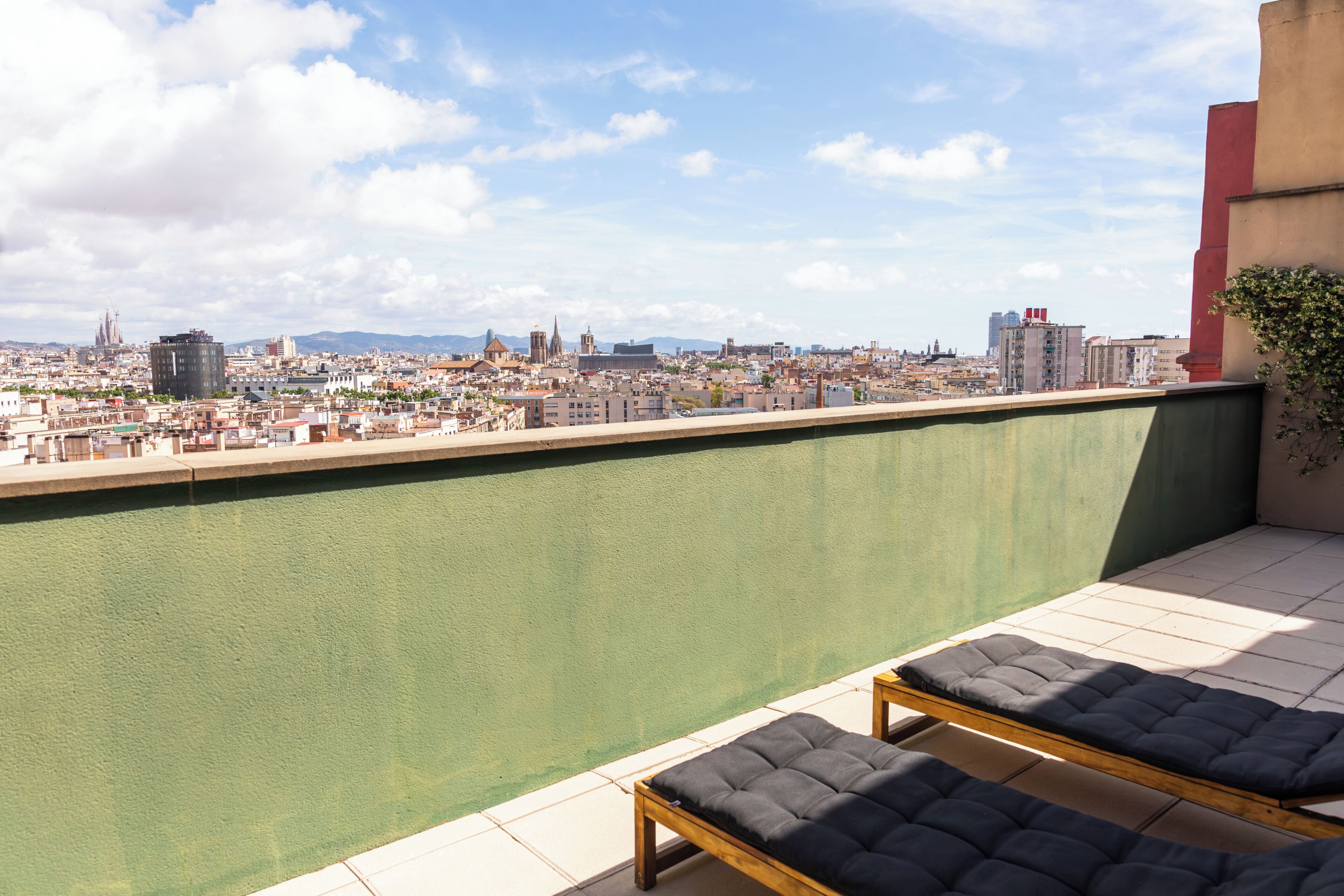 Eine Dachterrasse mit Blick auf die Stadt, einem Pool und Liegestühlen.
