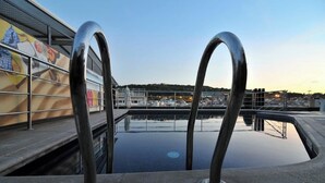 A swimming pool with metal railings and a view of a cityscape in the background. - Hotel Barcelona Universal (Barcelona)