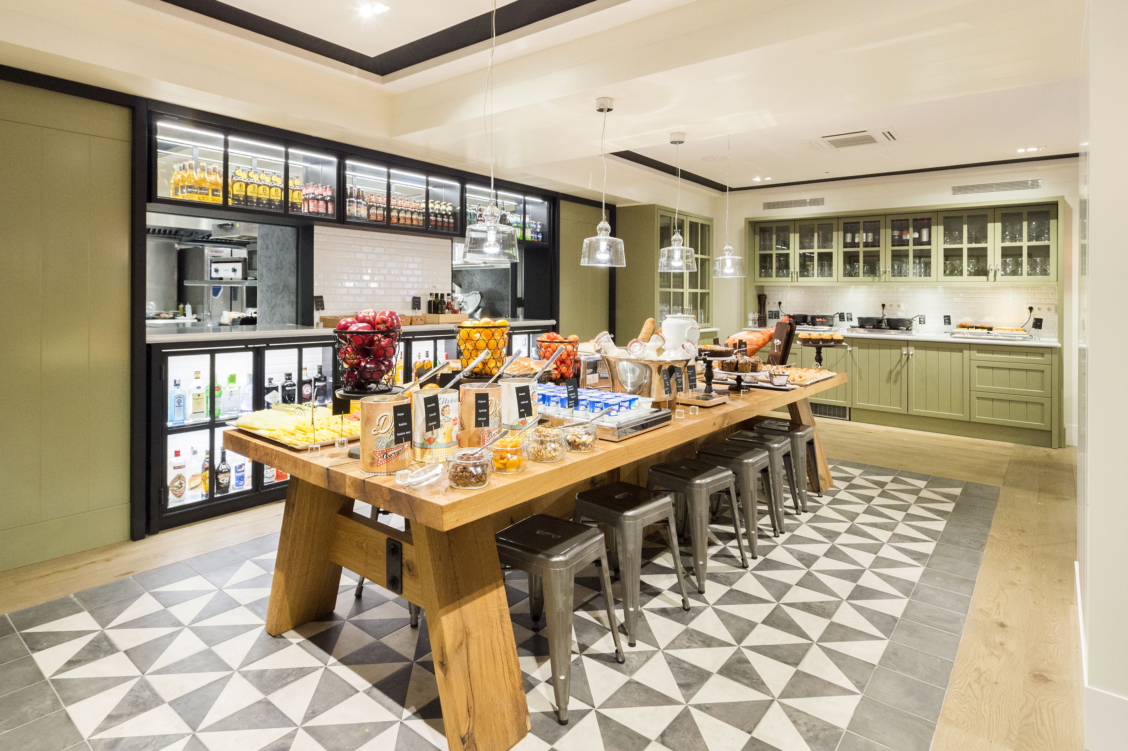 Una cuina moderna amb una illa central, seients de bar i una vitrina amb begudes.