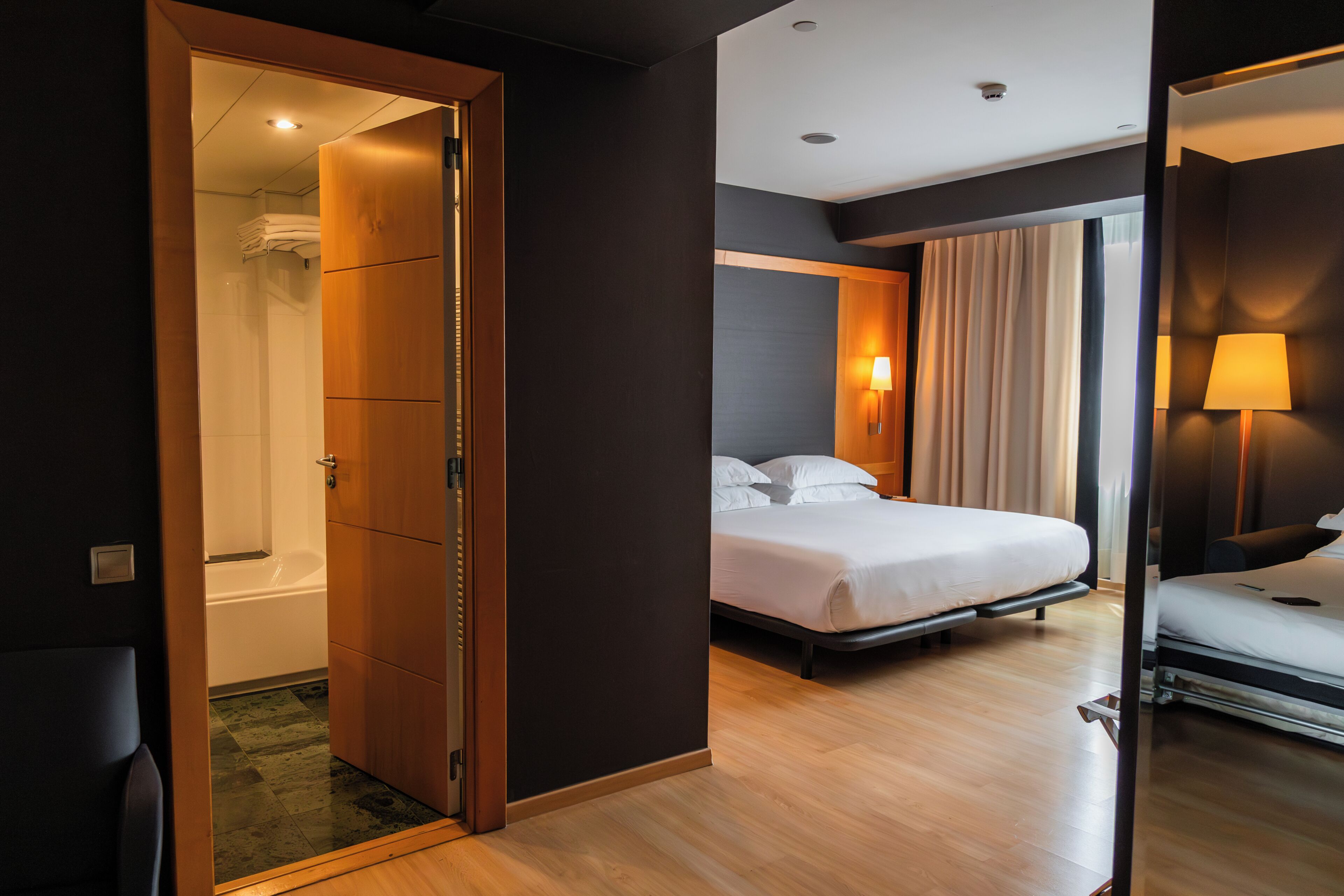 Une chambre d’hôtel avec un lit, une salle de bain avec douche et un miroir.