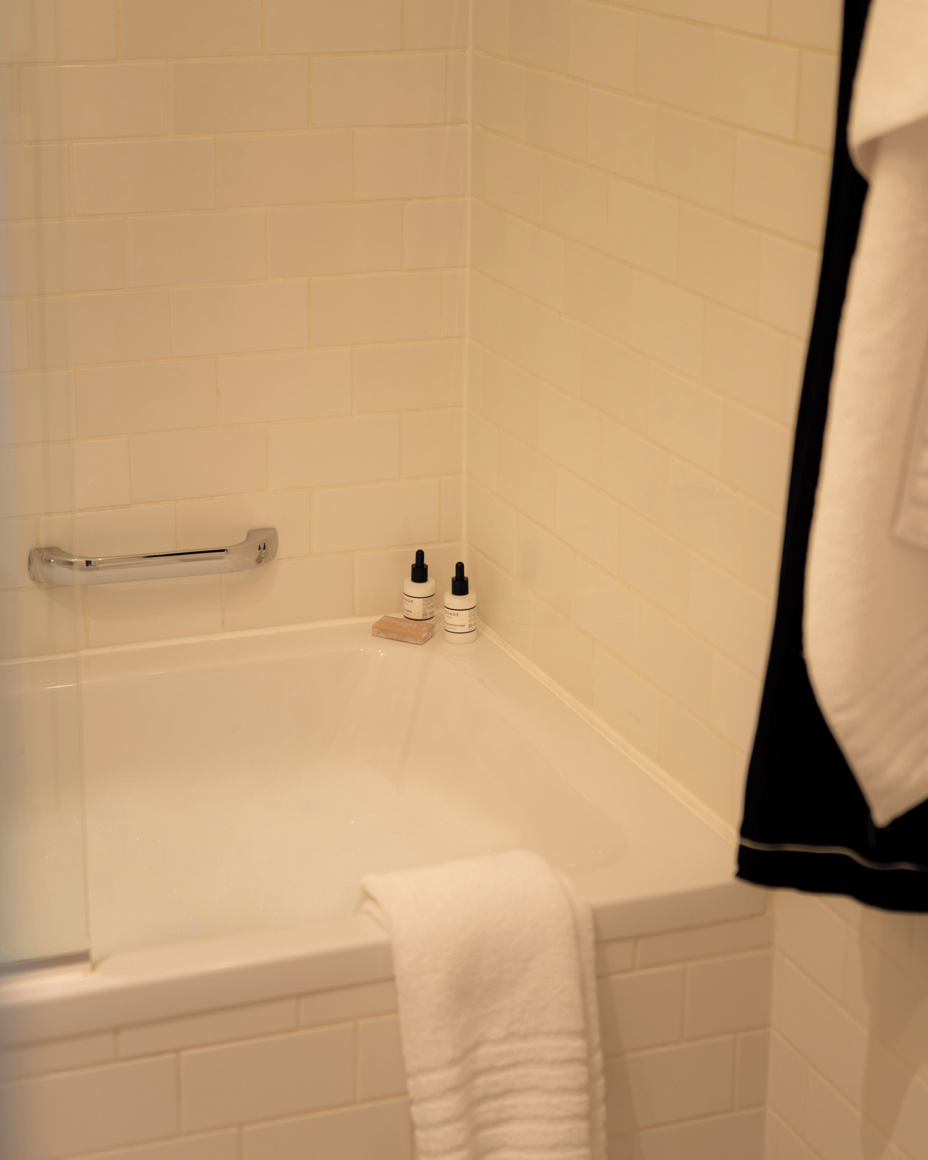 Un baño con una bañera, una toalla y dos botellas de champú.