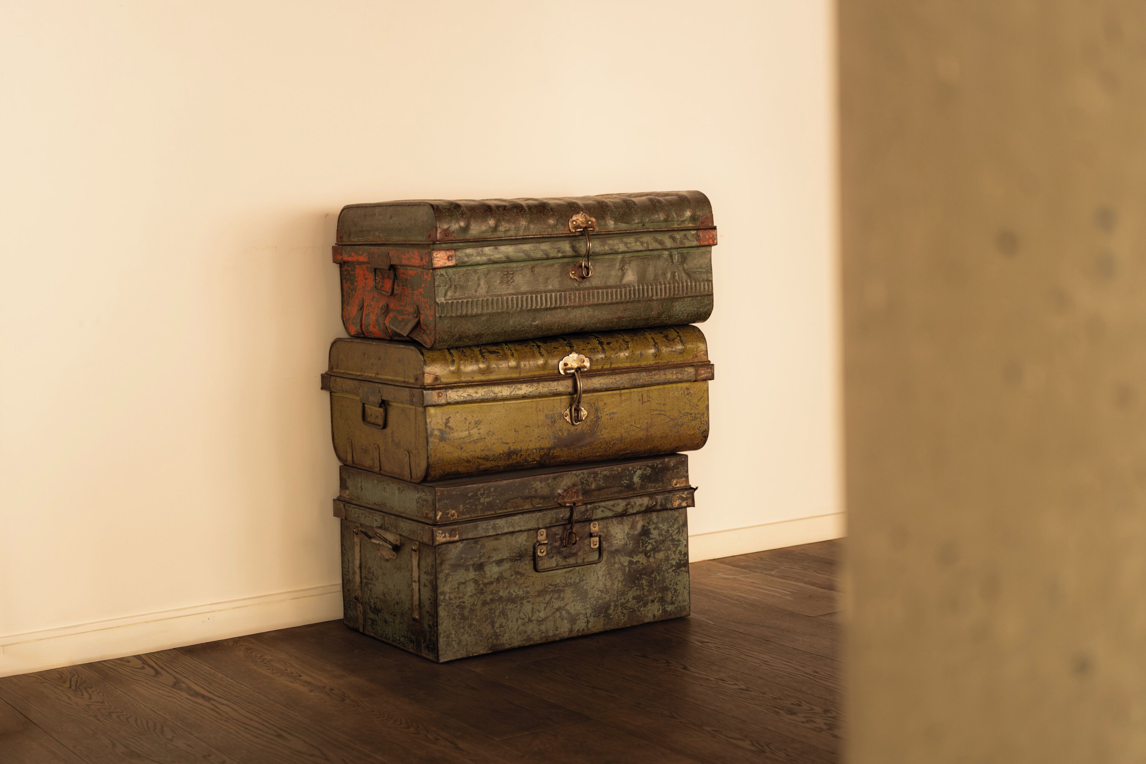 A stack of vintage suitcases against a plain wall.