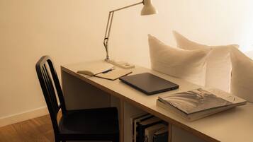 A desk with a laptop, a lamp, a notebook, and a book.