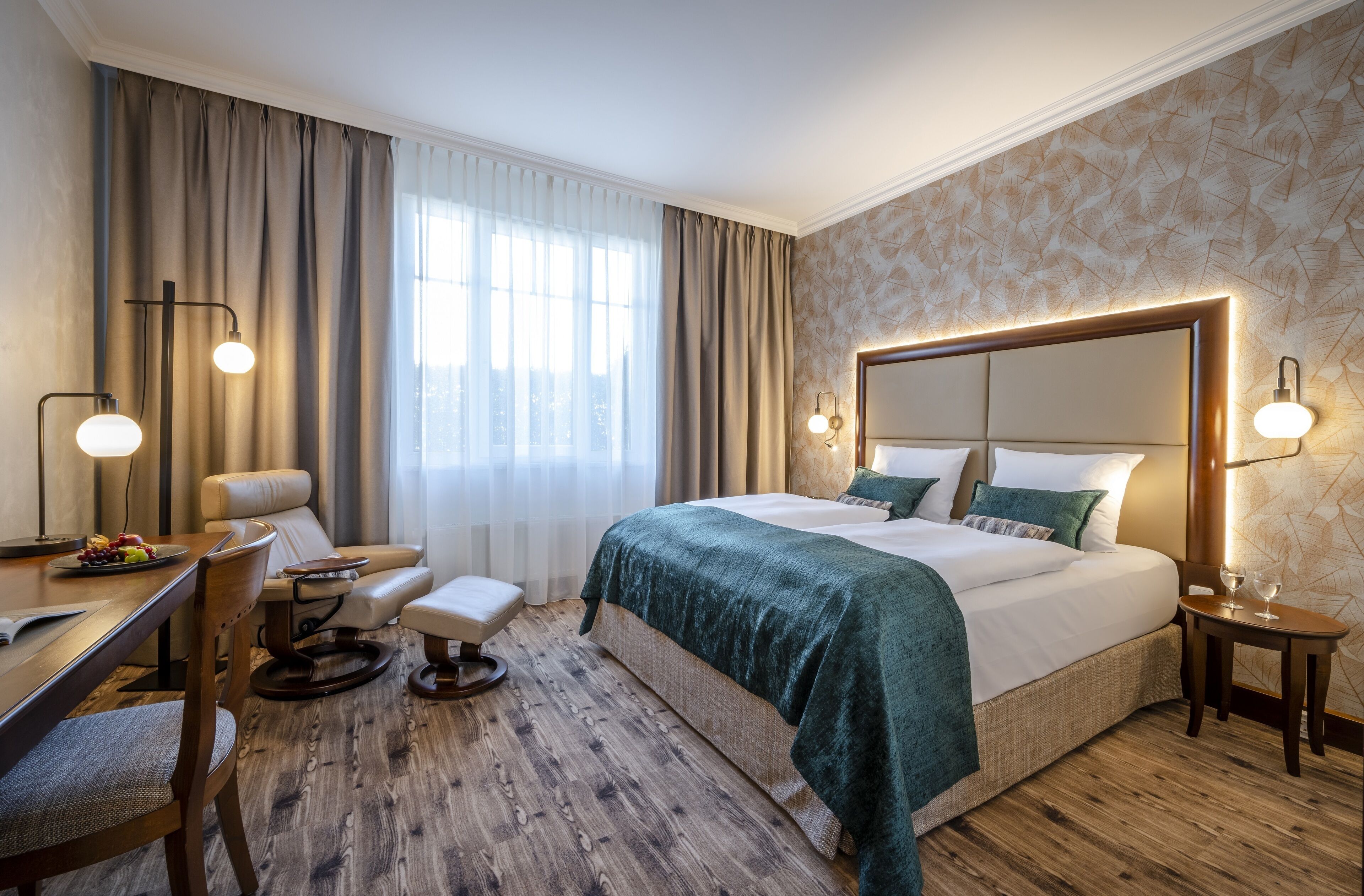 Een hotelkamer met een groot bed, een bureau met een stoel, een kleine tafel en een stoel.
