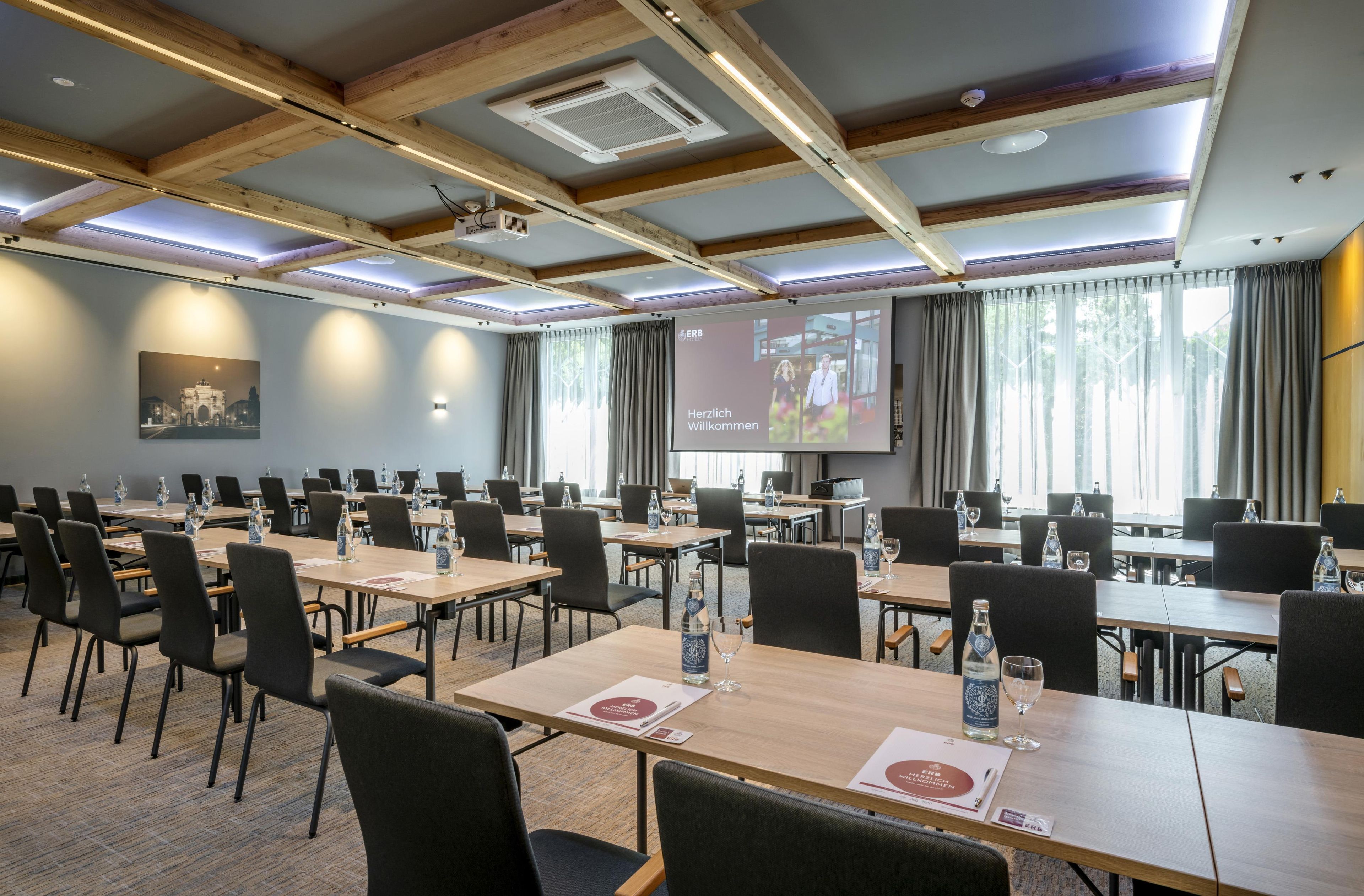 A conference room with multiple tables and chairs, a projector screen, and a large window with curtains.