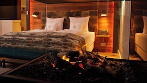 A modern hotel room with a large bed, a glass partition, and a visible fireplace. - Best Western Plus Hotel Erb (Vaterstetten)