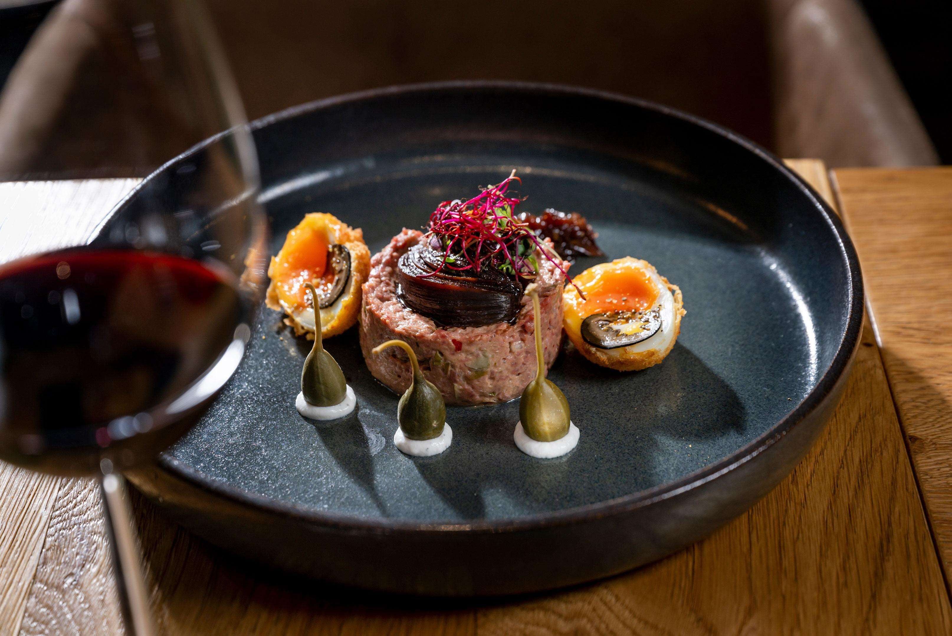 A plate of food with a wine glass.
