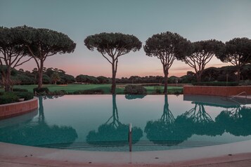 Una piscina cubierta, una piscina al aire libre, sombrillas