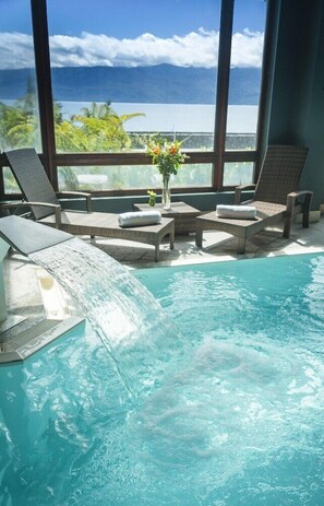 Alberca techada, alberca al aire libre y sombrillas en la alberca