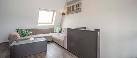 A modern living room with a grey sofa, a glass coffee table, and a flat-screen TV.