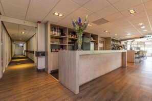 Eine Hotelhalle mit einer Rezeption, Holzböden und verschiedenen Annehmlichkeiten, darunter eine Bar und Regale mit Flaschen.