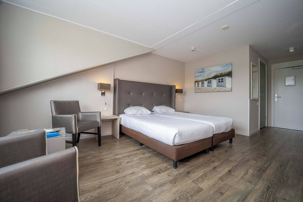 Una habitación de hotel moderna con una cama grande, un escritorio y una silla.