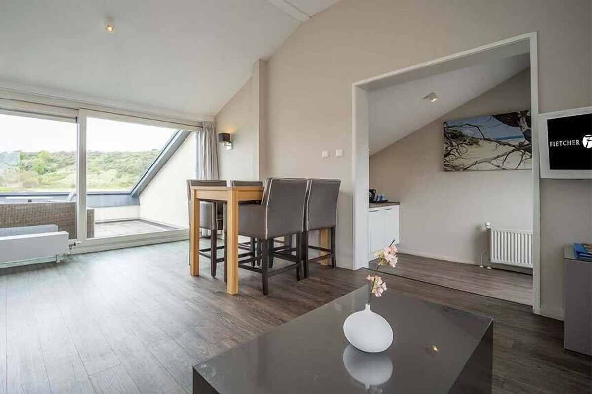 Un salon moderne avec un coin repas, de grandes fenêtres et une vue sur l’extérieur.