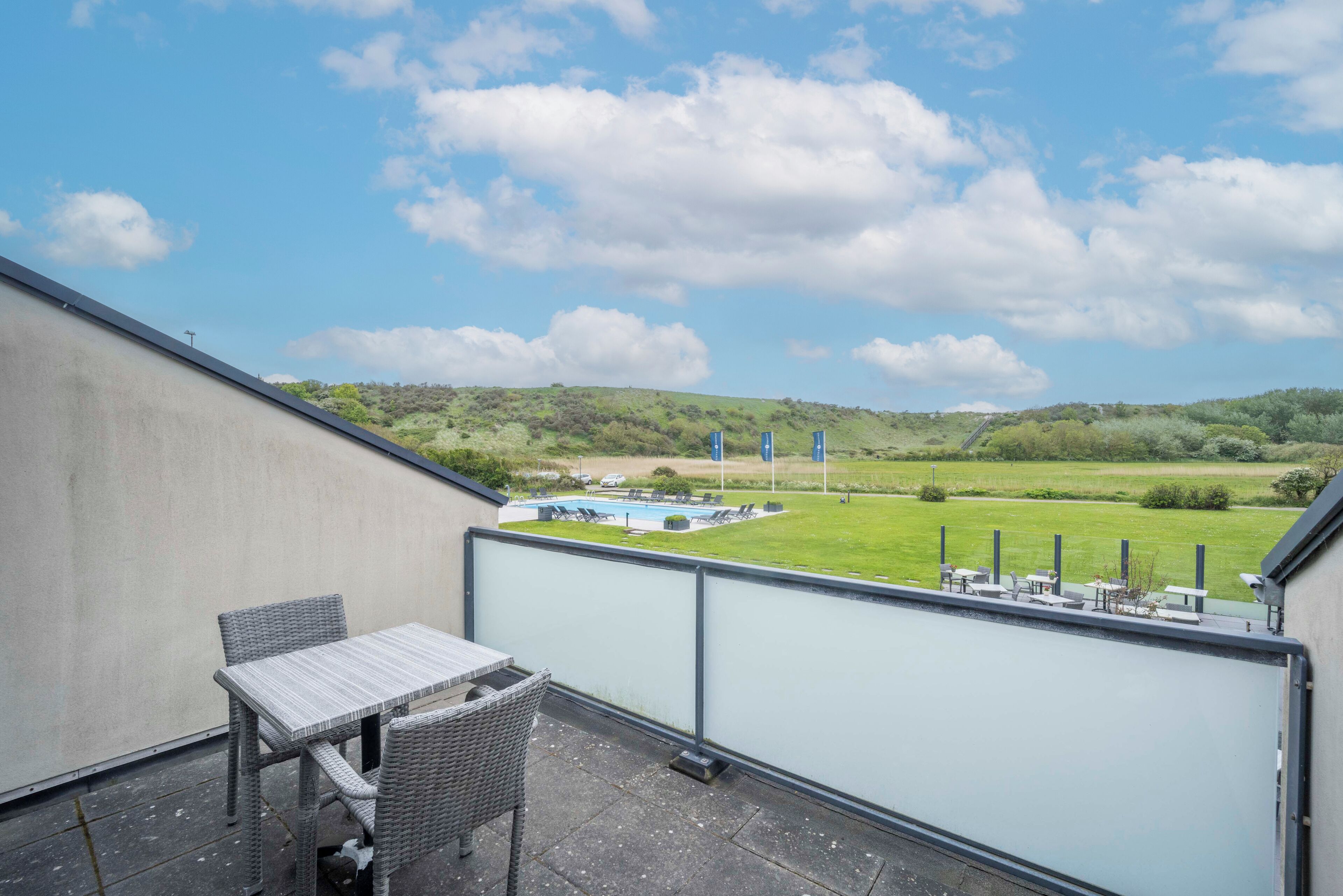 Un balcone con vista su una piscina e un'area verde.