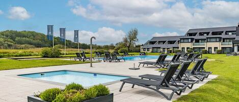 A modern outdoor pool area with lounge chairs and a landscaped garden.