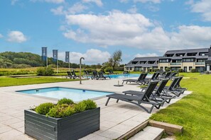 Ein moderner Poolbereich im Freien mit Liegestühlen und einem angelegten Garten.
