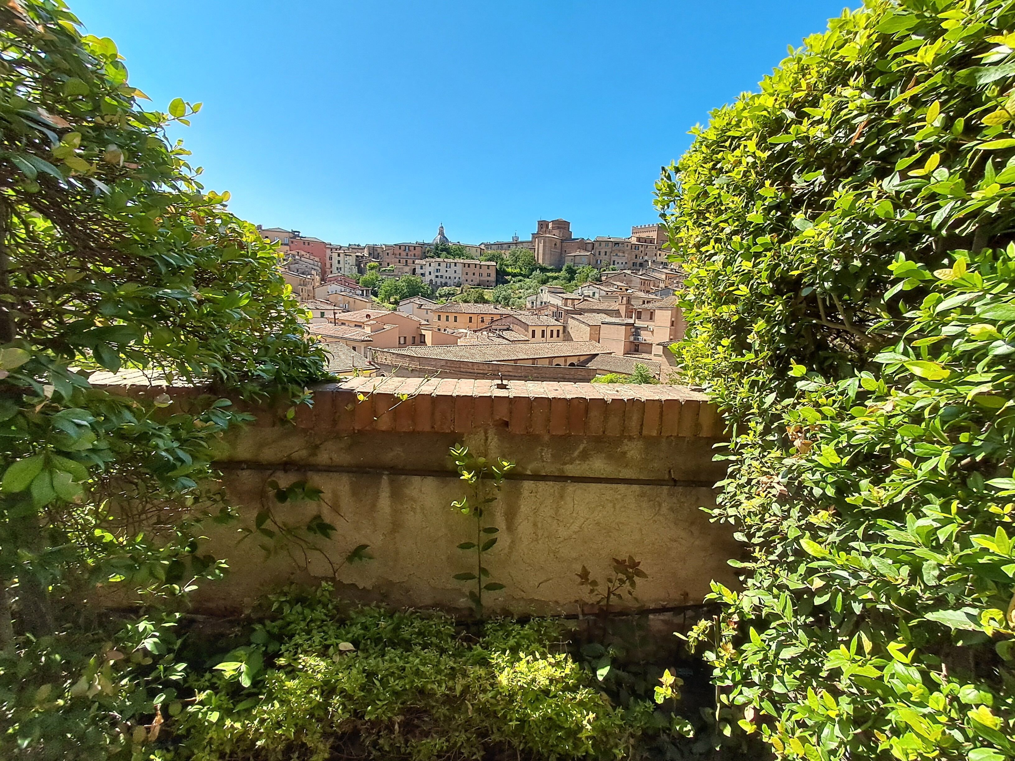 A view of a historic town with buildings, a prominent tower, and a stone wall in the foreground.