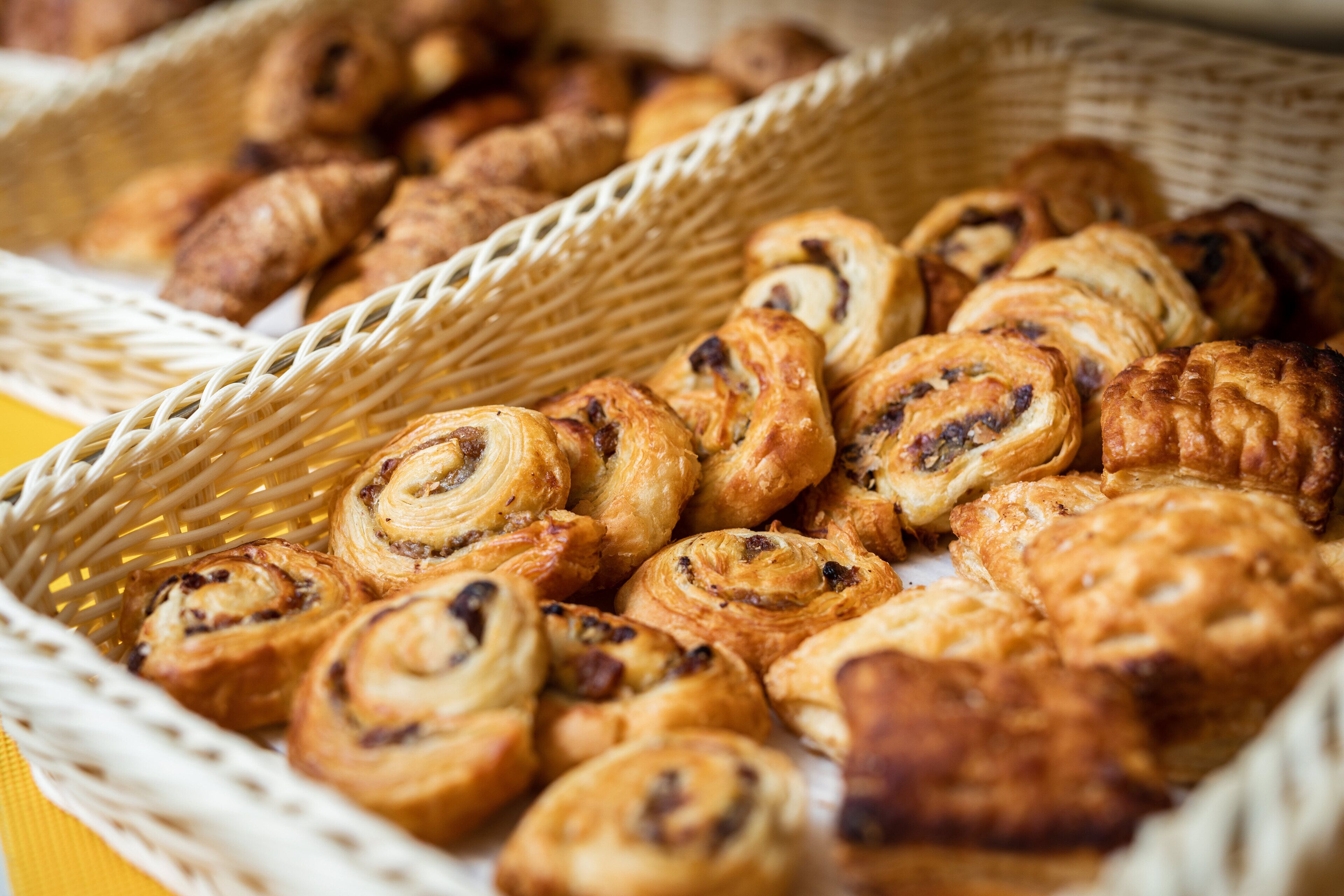 A basket filled with various pastries, including croissants and cinnamon rolls.