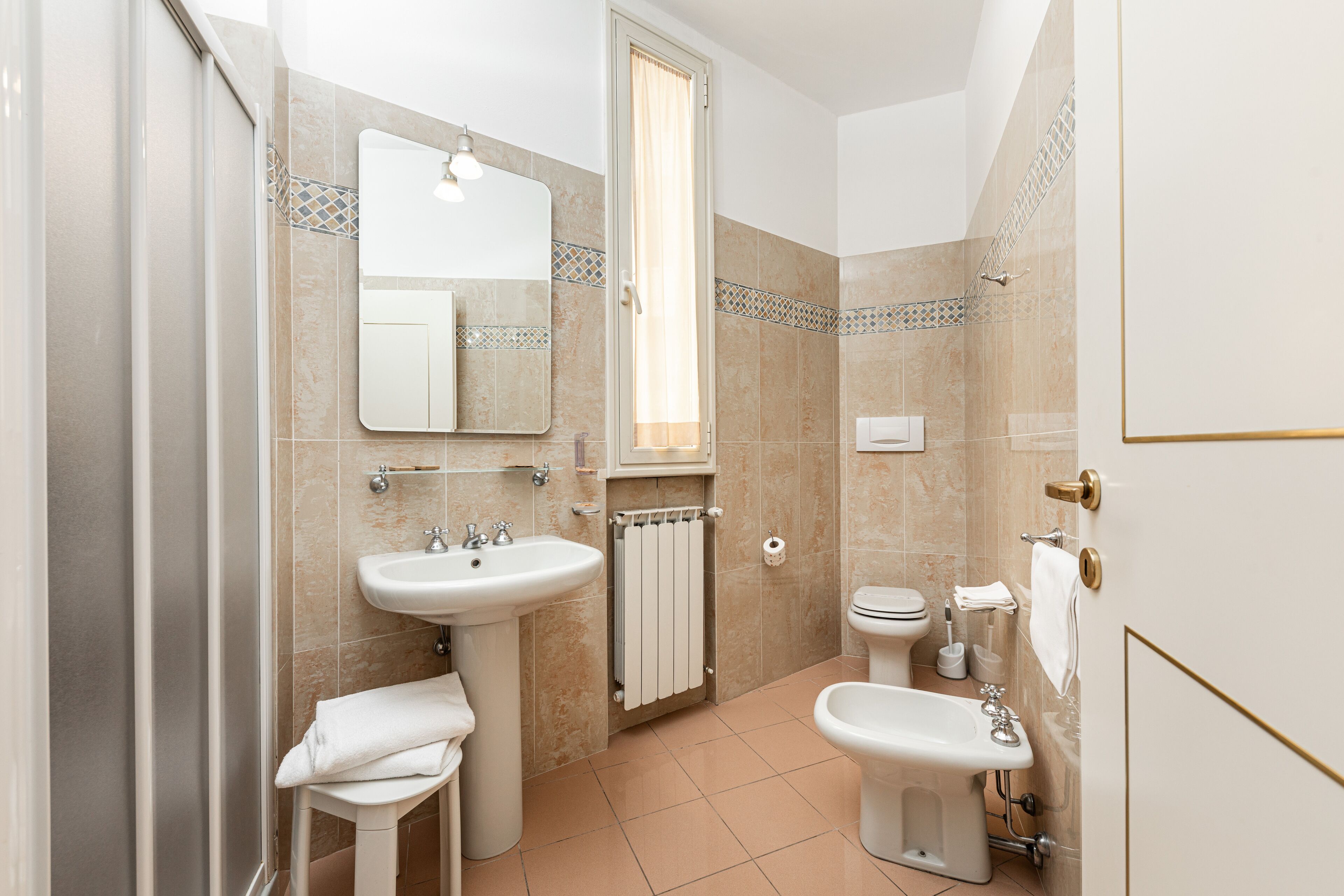 A bathroom with a sink, toilet, bidet, and shower.